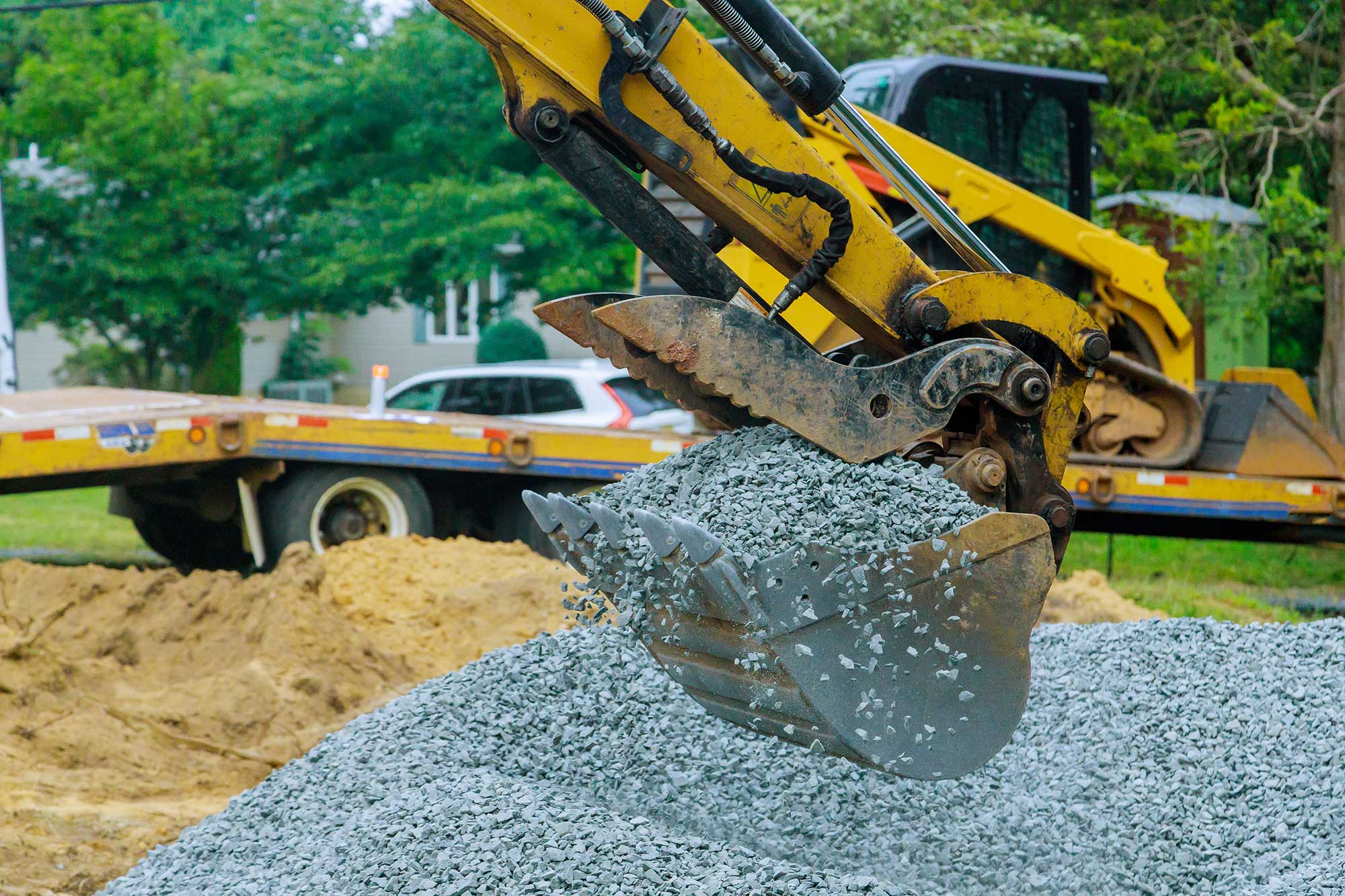 Excavation and base preparation for driveway paving with gravel.
