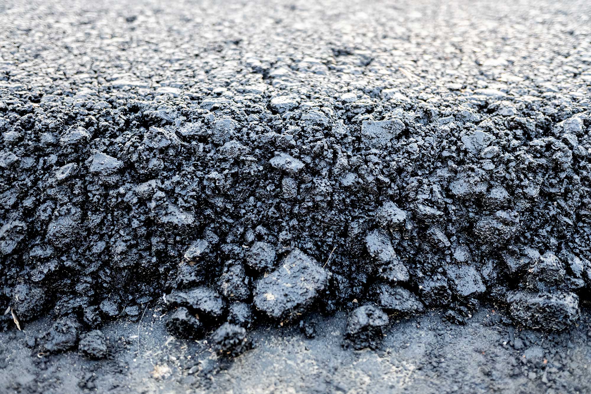 A close-up of compacted recycled asphalt, showcasing its rough texture and durability for paving projects