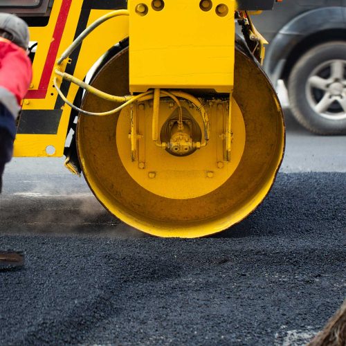 Workers laying asphalt for commercial paving in a parking lot.